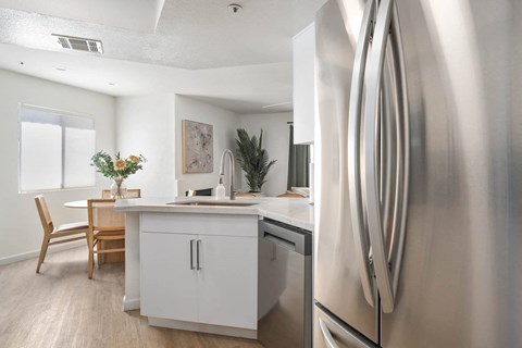 an open kitchen and dining room with stainless steel appliances and white cabinets